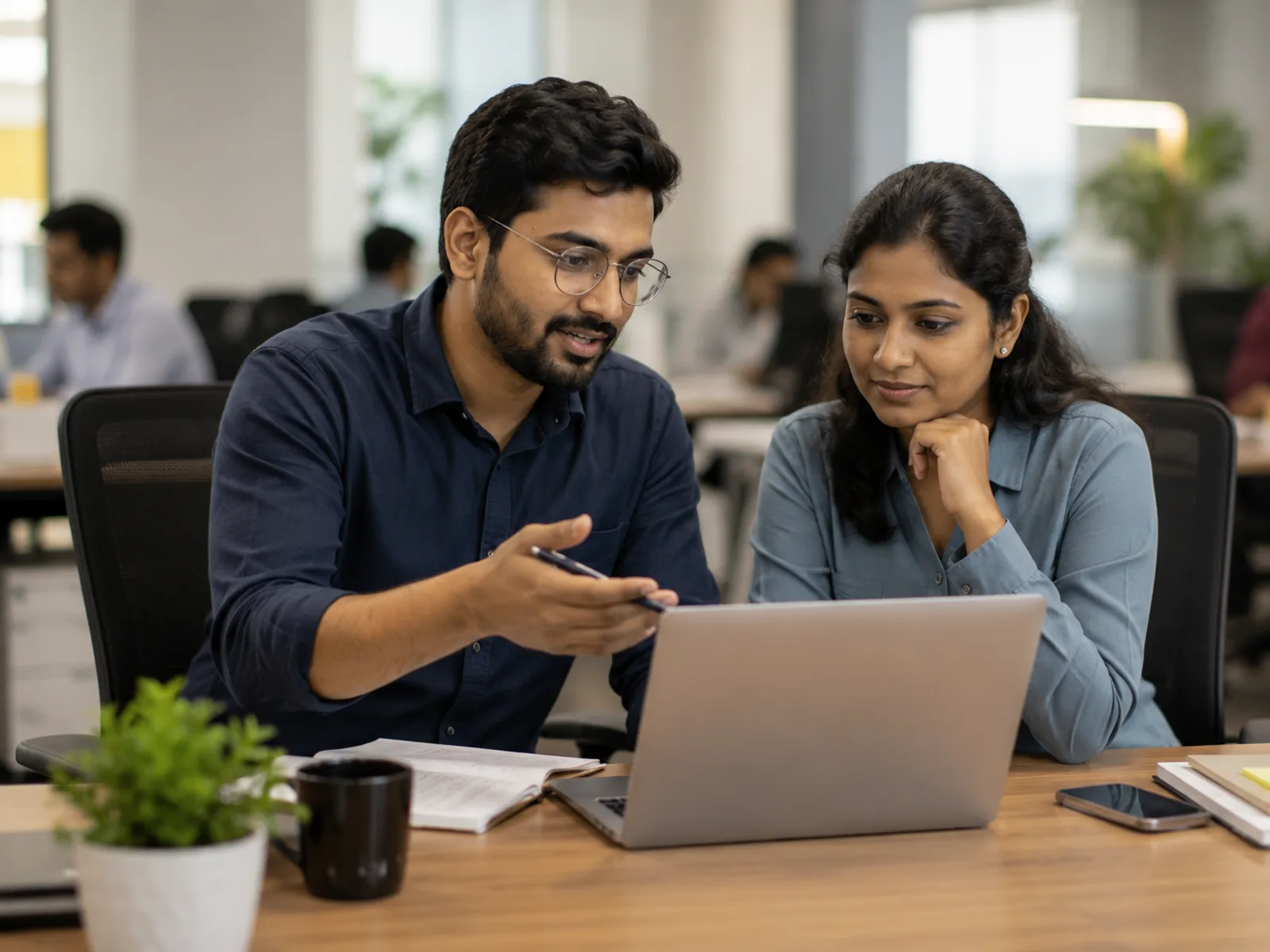 Two colleagues reviewing customer records together on a laptop